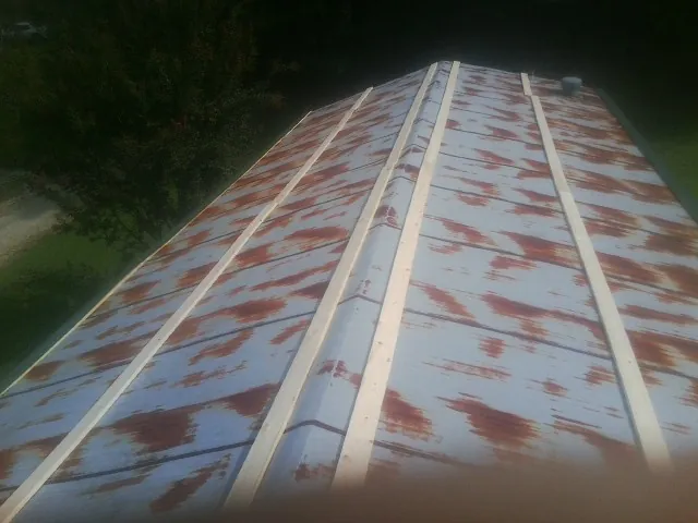 Rusted metal roof panels with new wood purlins before replacement — Storm Damage Roof Repair in Cypress Inn by Roofing Brothers