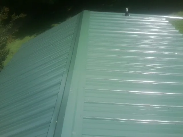 New green metal panels meeting at the ridge of a roof — Flat Roof Repair work by our crew in Cypress Inn