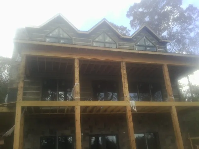Dormers and porch framing on a large log home under construction — Roof Coating work by our crew in Cypress Inn