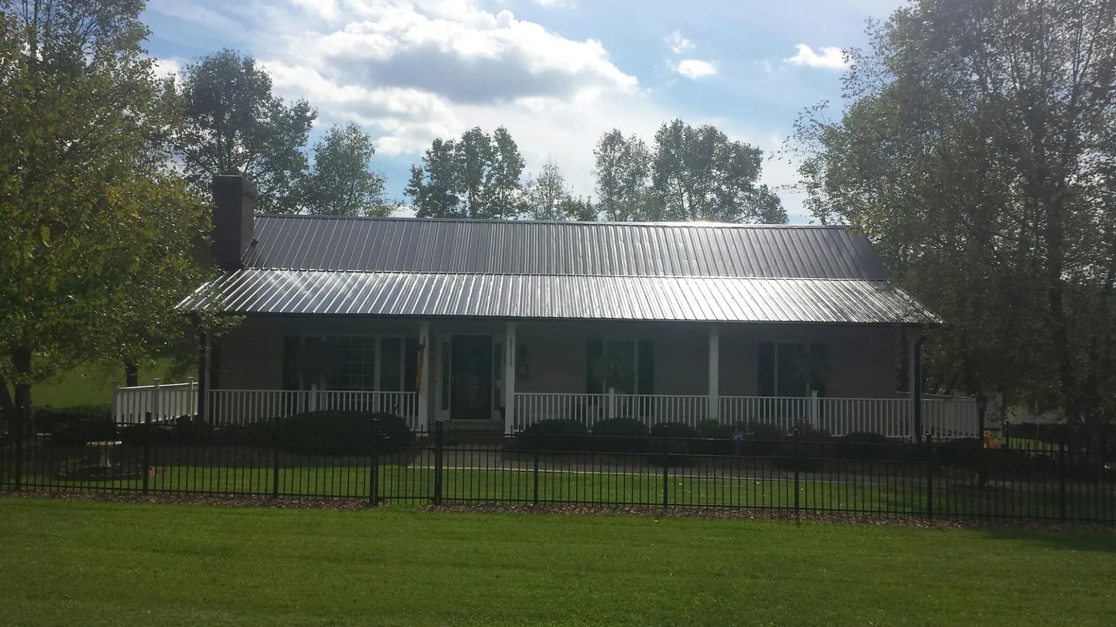 Gray metal roof on a brick ranch with a full width front porch — Gutter Guard Installation work by our crew in Cypress Inn